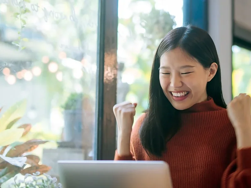 young asian female celebrating in front of her laptop because of improvements to the PESCI process.