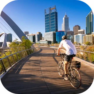 man riding on a bridge in Elizabeth Quay Perth. Skyscrapers in the background